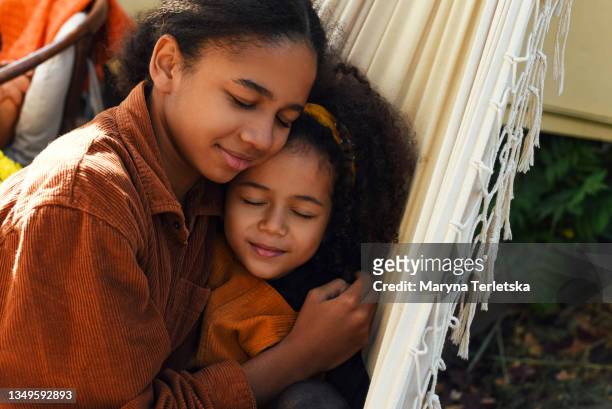 two dark-skinned girls are lying on a hammock with their eyes closed. - child eyes closed stock pictures, royalty-free photos & images