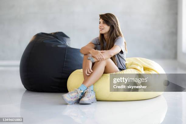 jeune femme pensive se relaxant dans un sac de haricots. - beanbag photos et images de collection