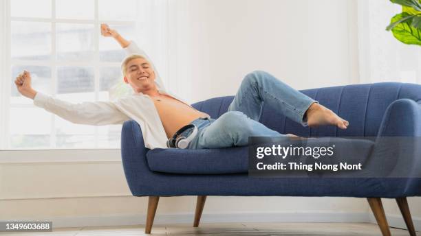 lgbt lonely man laughing happy on sofa relaxing at home. - fatigue full body stock-fotos und bilder