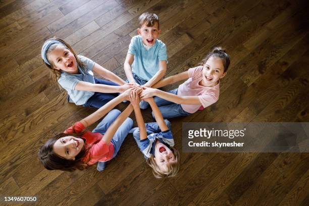 sopra la vista di bambini felici che uniscono le mani su un pavimento. - bambini seduti in cerchio foto e immagini stock