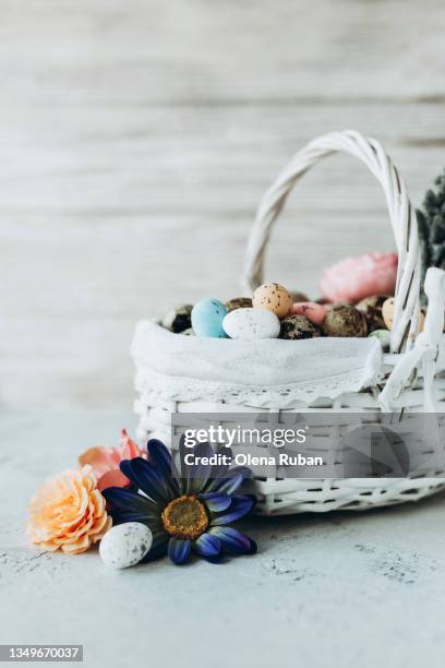 easter basket with flowers and eggs against white wall. - picnic basket stock pictures, royalty-free photos & images