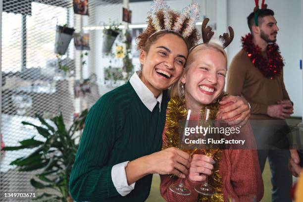 entzückende und aufgeregte multirassische kolleginnen, umarmt die weihnachtsfeier im büro - christmas party office stock-fotos und bilder