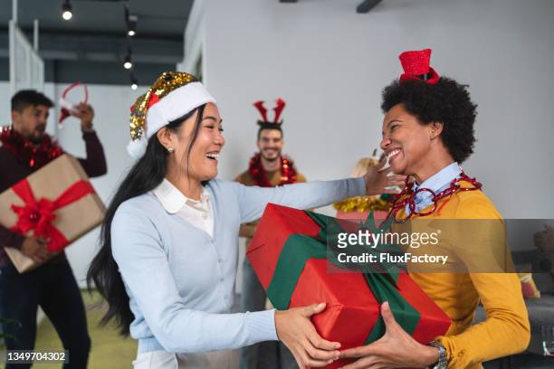 geschäftsfrauen asiatischer und afroamerikanischer abstammung genießen die weihnachtsfeier im büro - christmas party office stock-fotos und bilder