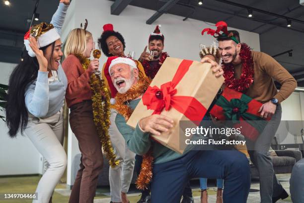 funny and carefree multiracial colleagues dancing during christmas party in the office - christmas party office stockfoto's en -beelden