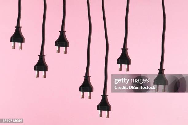 black cables with male plug hanging on pink background. electric energy and renewable energy concept. - high voltage sign stock pictures, royalty-free photos & images