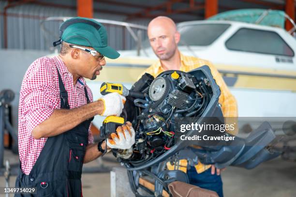 boat mechanic team has discussed with tightening the bolt to flywheel  to investigate the outboard motor engine in a boat repair workshop.outboard motor maintenance & engine restore concepts. - boat engine stock pictures, royalty-free photos & images