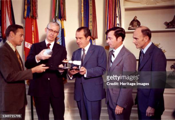 President Nixon with Dr. James Fletcher and Apollo 16 Astronauts, 1972. A model of the Apollo-Soyuz spacecraft with docking adapter is shown to...