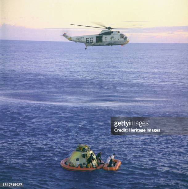 Apollo 10 Helicopter Recovery, 1969. A Navy helicopter arrivies to recover the Apollo 10 astronauts, seen entering a life raft, as the Command Module...