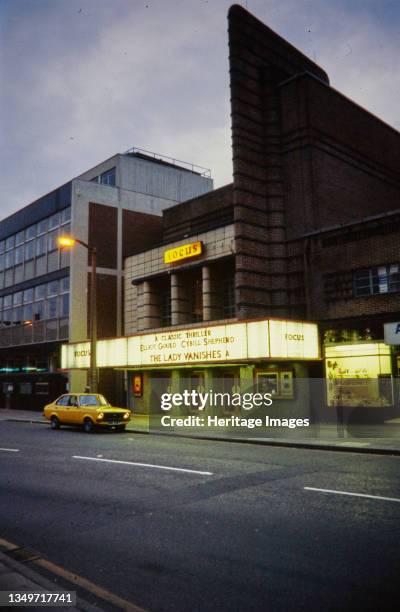 Focus Cinema, Delamere Street, Crewe, Cheshire East, 1975-1983. An exterior view of the Focus Cinema at dusk, showing the illuminated billboard. The...