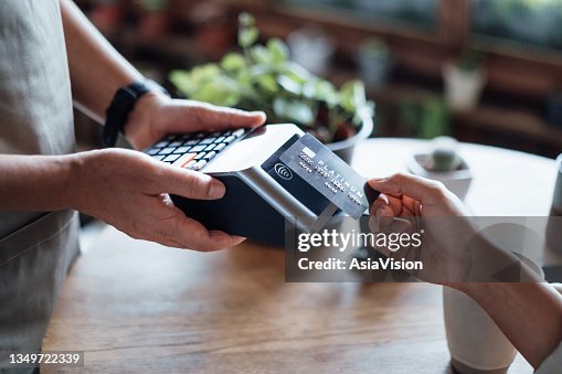 Nahaufnahme der Hand einer Frau, die in einem Café mit Kreditkarte rechnungsbezahlt und an einem Kartenautomaten scannt. Elektronische Zahlung. Banking und Technologie Nahaufnahme der Hand einer Frau, die in einem Café mit Kreditkarte rechnungsbezahlt und an einem Kartenautomaten scannt. Elektronische Zahlung. Banking und Technologie