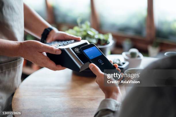 gros plan de la facture d’un homme payant à la main avec paiement sans contact par carte de crédit sur smartphone dans un café, numérisation sur une machine à cartes. paiement électronique. banque et technologie - paiement mobile photos et images de collection