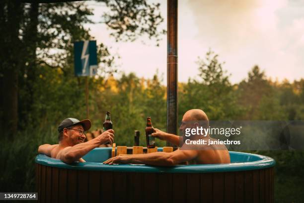 activités estivales. amis se baignant dans un bain à remous et prenant un verre - bain à remous photos et images de collection