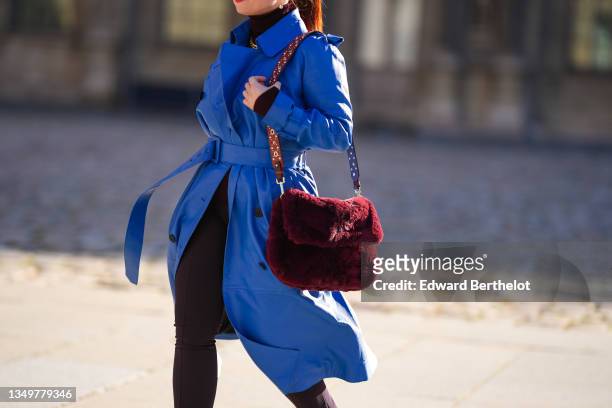 Nastasia Iavorscaia wears gold earrings, a gold large chain necklace, a burgundy ribbed turtleneck pullover, a royal blue electric leather long...