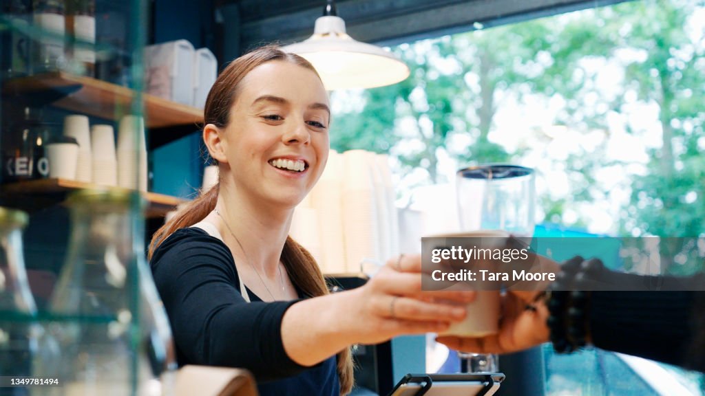 Woman serving coffee to customer