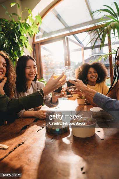 a group of friends is toasting together during a dinner party - frisdrank stockfoto's en -beelden