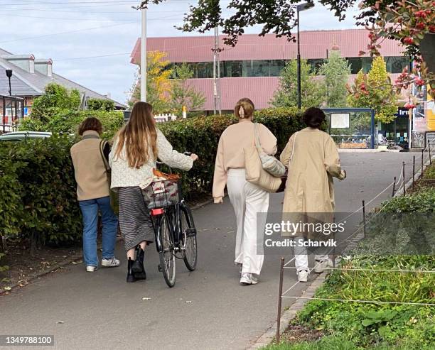 four young woman walking towards a bus stop at østerport, central copenhagen. - bus denmark stock pictures, royalty-free photos & images