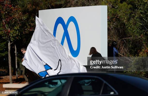 Facebook employees unveil a new logo and the name 'Meta' on the sign in front of Facebook headquarters on October 28, 2021 in Menlo Park, California....