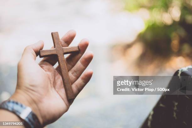 cropped hand holding cross - crucifixion stock-fotos und bilder
