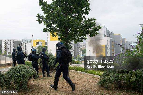 Police monitor a fire set by demonstrators near apartment buildings following a march protesting the shooting of Nahel by a police officer in the...