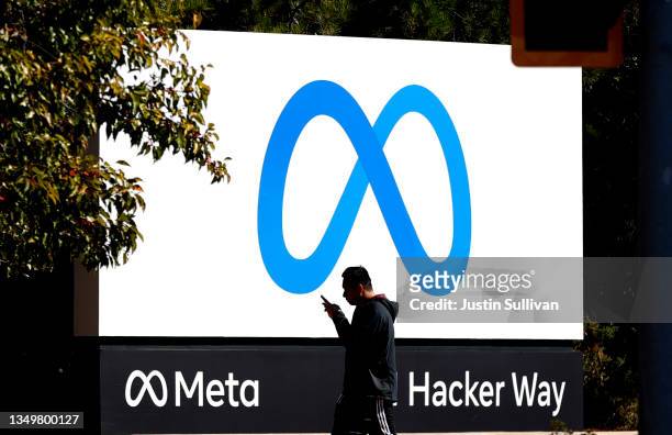 Pedestrian walks in front of a new logo and the name 'Meta' on the sign in front of Facebook headquarters on October 28, 2021 in Menlo Park,...