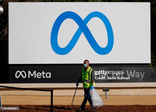 Worker picks up trash in front of a new logo and the name 'Meta' on the sign in front of Facebook headquarters on October 28, 2021 in Menlo Park,...