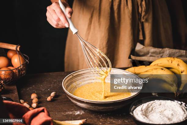 donna che prepara la pastella di pane alla banana in cucina a casa - whisk foto e immagini stock