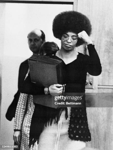 Black activist Angela Davis gives the "Black Power" salute as she enters Santa Clara County Superior Court. In back is Defense Attorney Leo Branton...