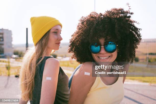 happy teenage girls with adhesive bandage on their hands after vaccination - name patch stock pictures, royalty-free photos & images