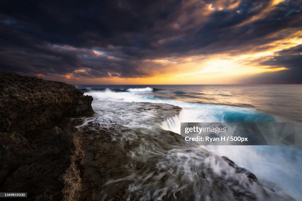 Scenic view of sea against cloudy sky during sunset