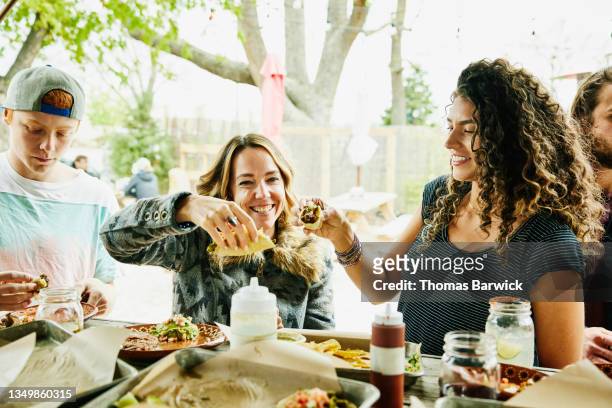 Medium wide shot of smiling female friends toasting with tacos while dining at food truck