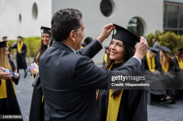 proud father arranging the mortarboar of her graduating daughter - graduates stockfoto's en -beelden