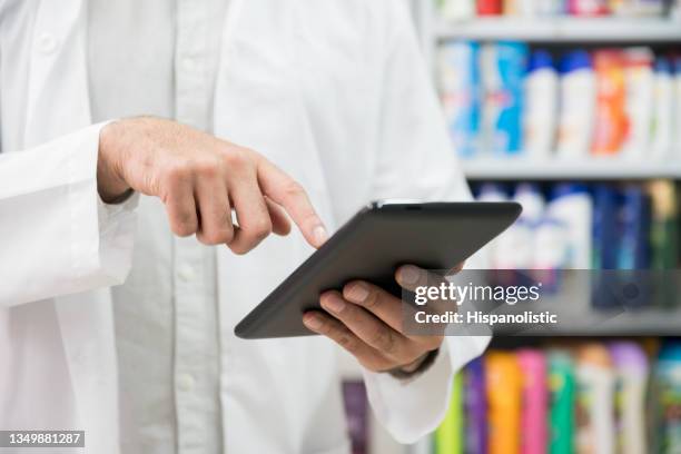 nahaufnahme eines nicht wiederzuerkennbaren männlichen apothekers, der eine bestellung auf tablette betrachtet - ersuchen stock-fotos und bilder