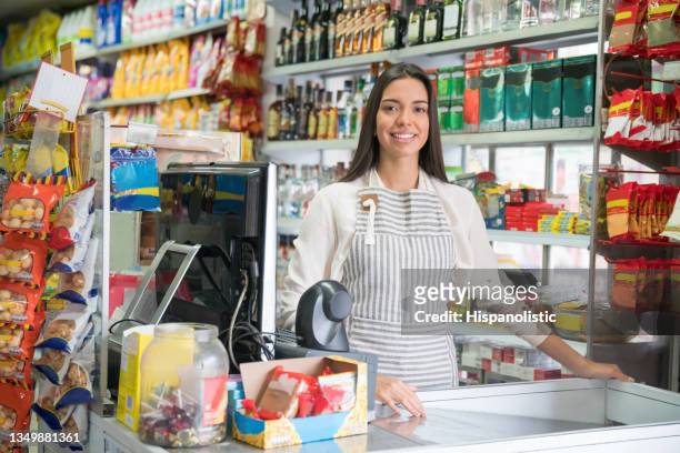 cheerful cashier at a convenience store smiling at camera with a toothy smile - 收銀機 個照片及圖片檔