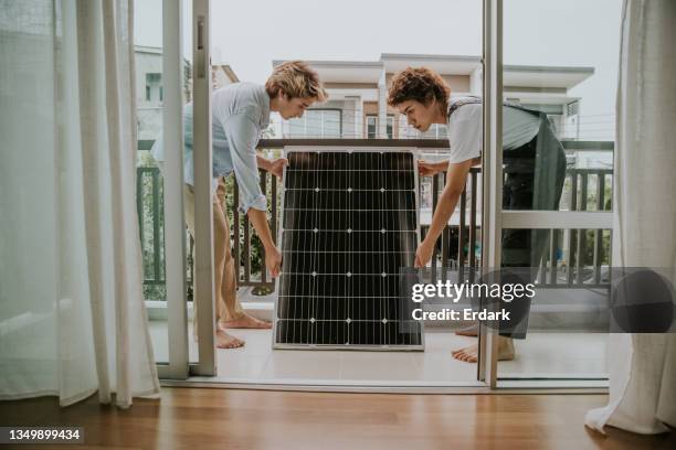 pareja gay está instalando panel solar en el balcón de la casa-foto de archivo - balcon fotografías e imágenes de stock