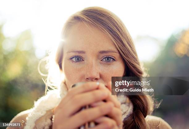 young women drinking warm tee in autumn park - woman drinking tea stock-fotos und bilder