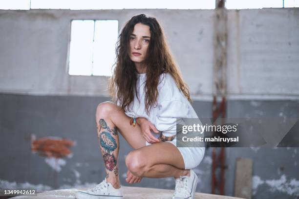 young woman in abandoned building. - one woman only kneeling stock pictures, royalty-free photos & images