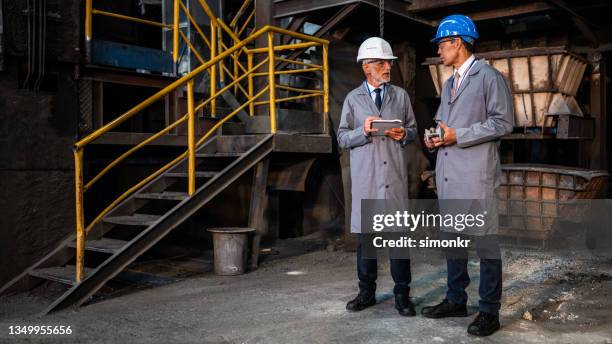 male engineers examining metal equipment in a foundry. - protective eyewear stock pictures, royalty-free photos & images