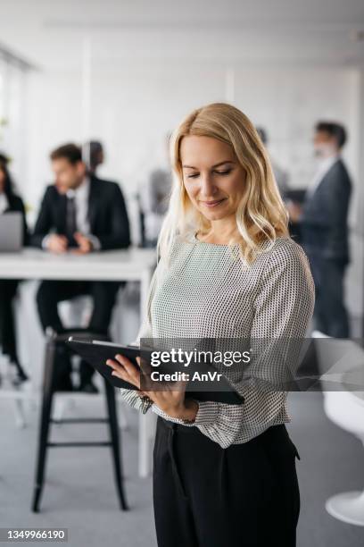 good-looking business woman working on her tablet - 40 50 business woman stock pictures, royalty-free photos & images