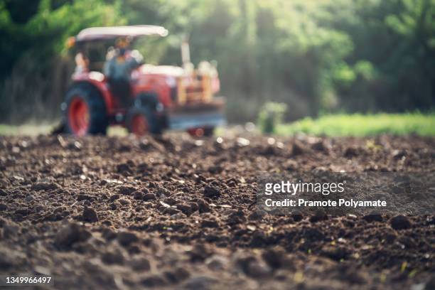 select focus of potting soil, agricultural worker with tractor preparing land with seedbed cultivator as part of pre seeding activities in early spring season of agricultural works at field. - soil ストックフォトと画像