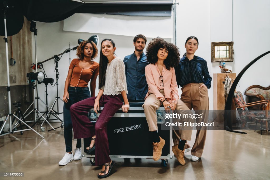 Ritratto di un gruppo creativo di persone in un moderno loft con attrezzatura fotografica sullo sfondo