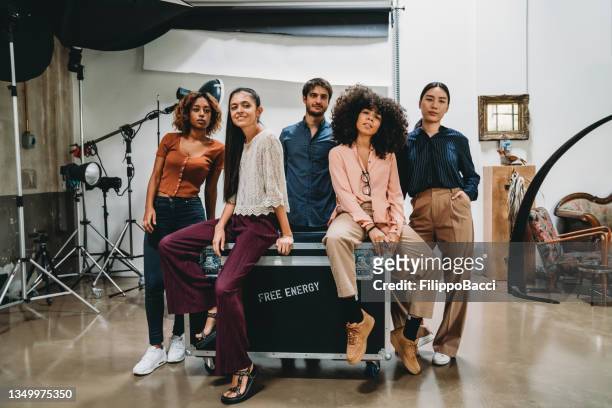 portrait of a creative group of people in a modern loft with photographic equipment in the background - organised group photo stock pictures, royalty-free photos & images