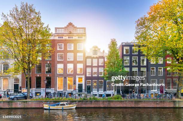 sunset over old houses in amsterdam, netherlands - amsterdam canal stockfoto's en -beelden