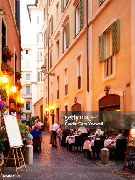 people dining outside in trastevere district in rome at dusk - trastevere stock-fotos und bilder