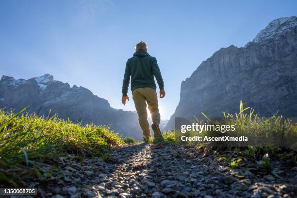 el hombre camina a lo largo de la cresta de la montaña cubierta de hierba al amanecer - mirar hacia delante fotografías e imágenes de stock