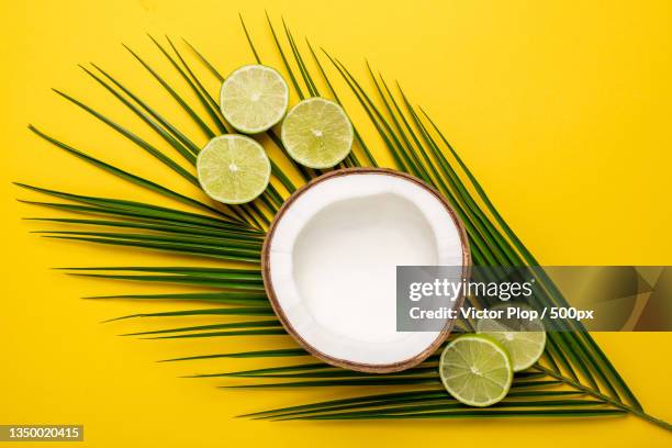 directly above shot of coconut with coconut and leaves on yellow background - papaya stock-fotos und bilder