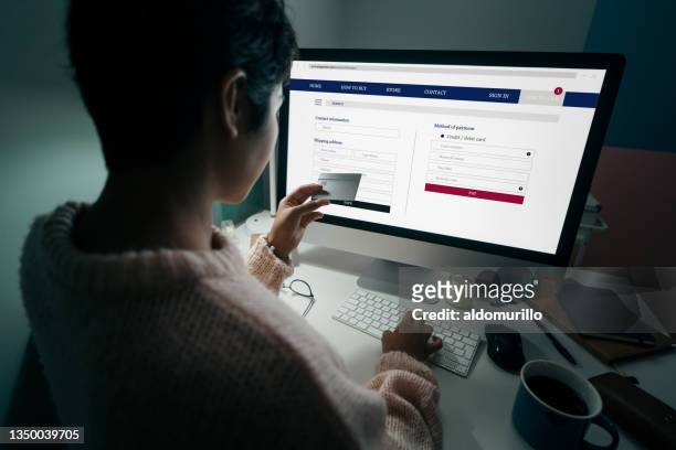 woman holding credit  card in front of computer while shopping online. - person with in front of screen stockfoto's en -beelden