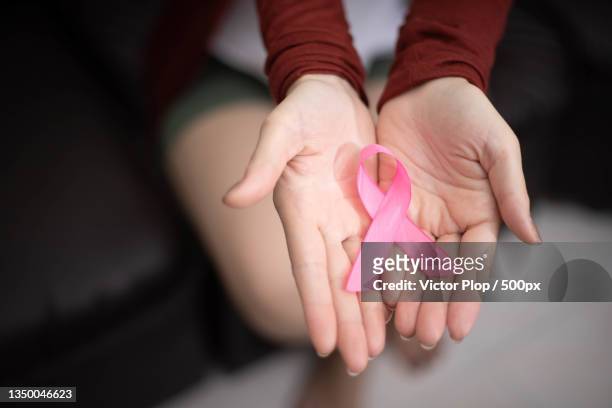 midsection of woman holding pink breast cancer awareness ribbon - dia mundial do cancro imagens e fotografias de stock