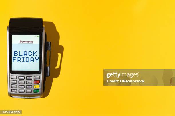 dataphone with the word 'black friday' on the screen on yellow background at the left side. black friday, shopping, commerce and credit cards concept. - black friday shopping stockfoto's en -beelden