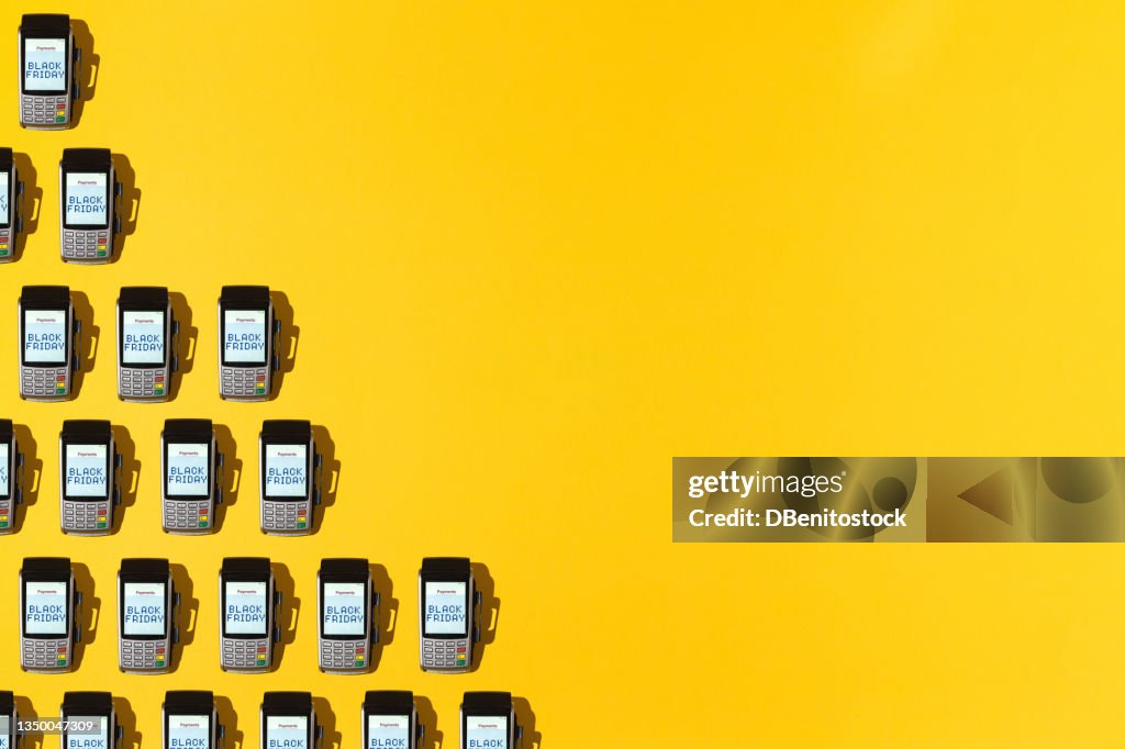 Dataphones pattern with the word 'Black Friday' on the screen on yellow background on top line, with copy space. Black friday, shopping, commerce and credit cards concept.