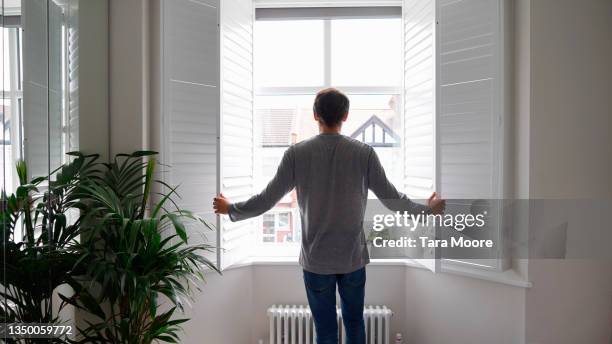 man opening shutters in house - persiane foto e immagini stock